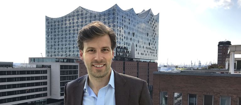 Exporo-Immobilienchef Julian Oertzen über den Dächern von Hamburg. Im Hintergrund: die Elbphilharmonie. 